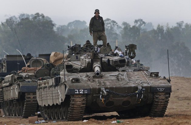 An Israeli soldier stands on a tank at a staging area near the Israel Gaza Strip Border, southern Israel, early Tuesday, Nov. 20, 2012. U.N. Secretary-General Ban Ki-moon is urging Israeli forces and Gaza militants to hold their fire, warning that a further escalation of the seven-day-old conflict would endanger the entire region. (AP Photo/Lefteris Pitarakis)